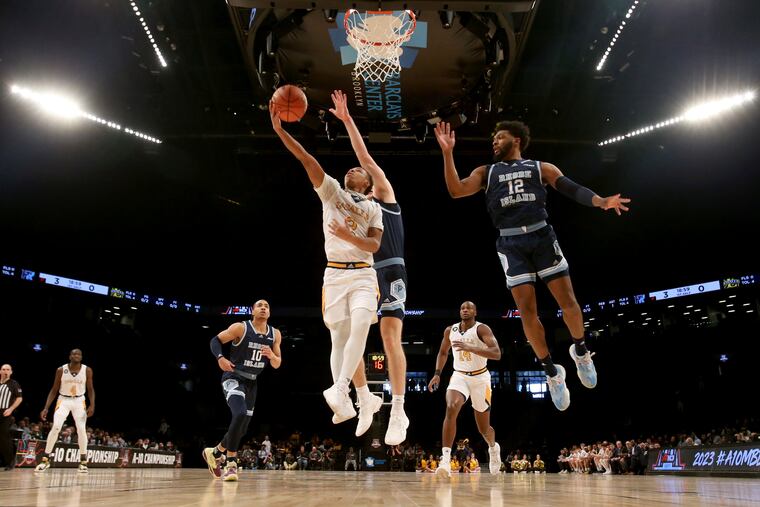 Jhamir Brickus (left) of La Salle scores against Rory Stewart (center) and Jeremy Foumena of Rhode Island during the Atlantic 10 Men's tournament at the Barclays Center in Brooklyn, N.Y. on March 7, 2023.