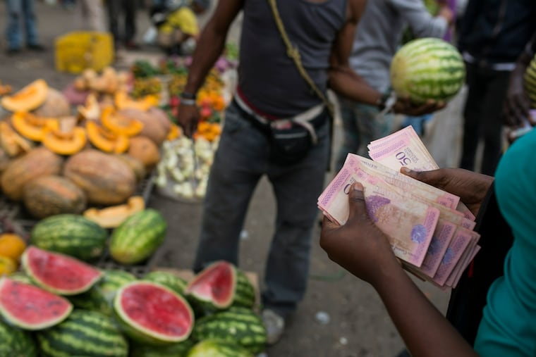 A fruit vendor counts his Bolivares in the Coche Market in Caracas, Venezuela, Thursday, May 2, 2019. Farmers truck in the produce, meat and coffee from miles around the capital to the market known for its low prices. Its customers include everybody from restaurant owners to homemakers. (AP Photo/Rodrigo Abd)