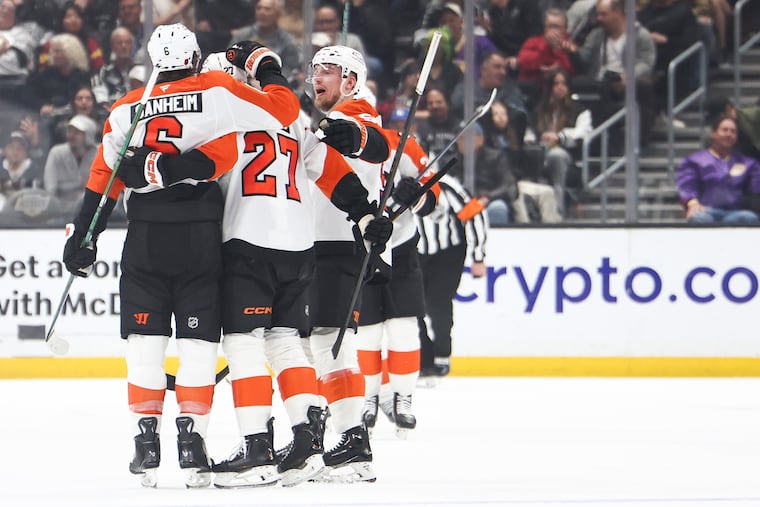 Travis Sanheim (left) celebrates with Noah Cates (center) and Rasmus Ristolainen after Sanheim's second period goal against the Kings.