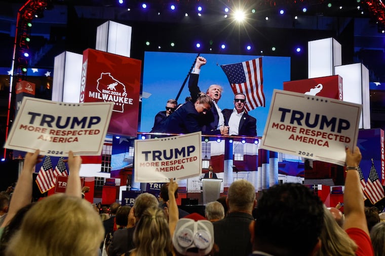 Donald J. Trump Jr., addresses the Republican National Convention at the Fiserv Forum in Milwaukee on Thursday as an image of his father, former President Donald Trump, raising his fist after a Saturday assassination attempt is projected inside the arena.