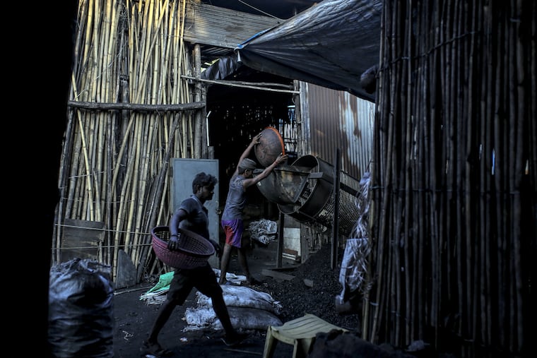 A worker unloads a bowl of charcoal onto a wire mesh filter at a coal wholesale market in Mumbai, India. (Dhiraj Singh / Bloomberg)