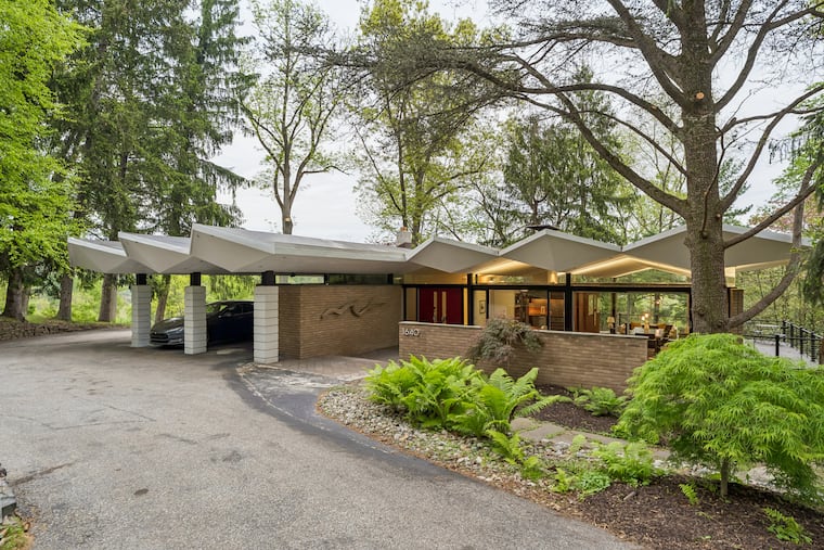 The home has a geometric roof that extends over a car port.
