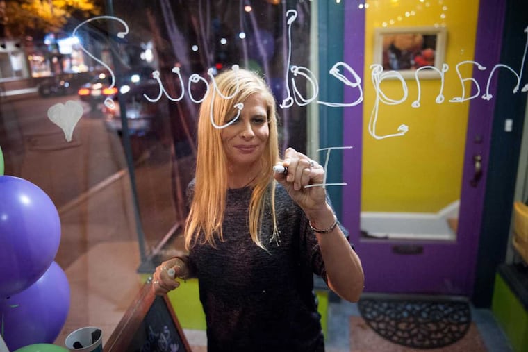Carole Rossi, of Audubon, writes about what yoga has given her on the window of Yogawood studio during a party to celebrate the studio's 10th anniversary in Collingswood, N.J. on Saturday, Nov. 12, 2016. Owner Beth Filla considered cancelling the party after the presidential election.