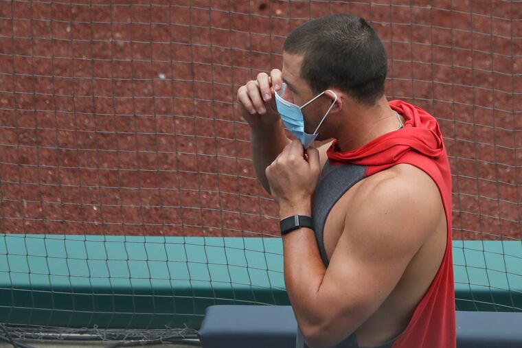 Phillies catcher J.T. Realmuto puts a face mask on after leaving the dugout during training camp at Citizens Bank Park on Saturday.