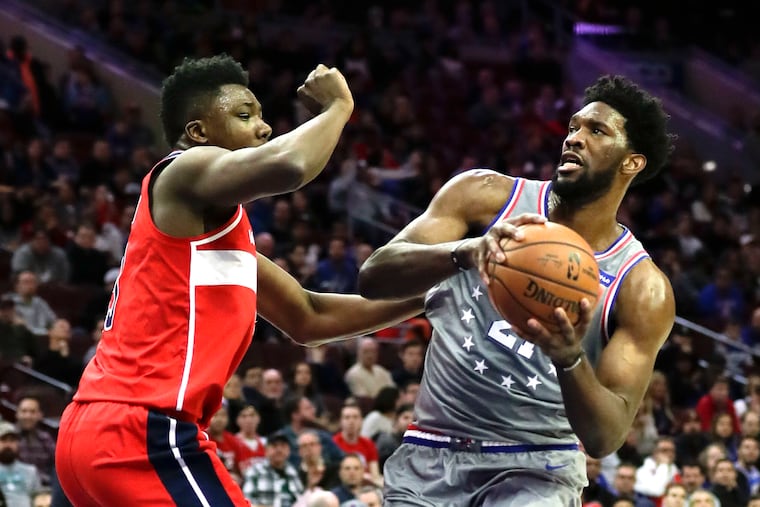 Sixers center Joel Embiid (right) drives to the basket against Washington Wizards center Thomas Bryant on Friday, November 30, 2018 in Philadelphia.