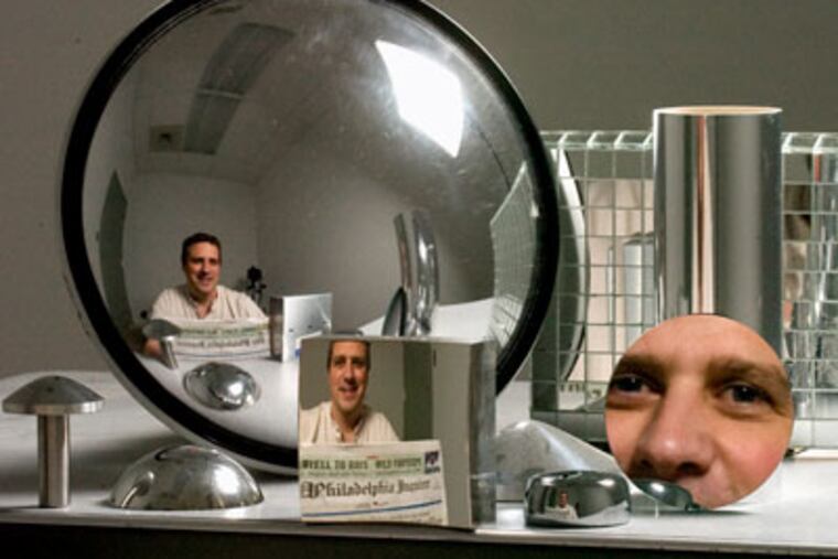 Andrew Hicks, reflected in and among mirrors he has designed. The one in the middle - with the Inquirer print readable - is a non-reversing mirror. (Clem Murray / Staff Photographer)