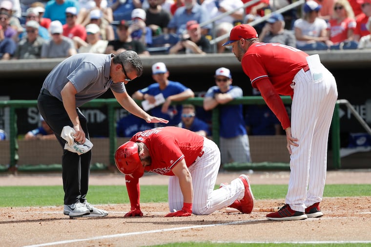 Bryce Harper is visited by Phillies manager Gabe Kapler (right) and trainer Chris Mudd after getting hit by a pitch on Friday.