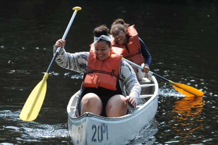Destiny Colon (front), 13, and Arianna Boyer, 12, both from Camden, push off from shore in a canoe on Lummy Lake in Belleplain State Forest, Woodbine, NJ, July 31, 2014. The girls are part of a group of 150 kids from Camden participating in the Rowan University CHAMP program, which included an overnight in tents in the forest and recreation time to swim and canoe in the lake before going home. ( CLEM MURRAY / Staff Photographer )