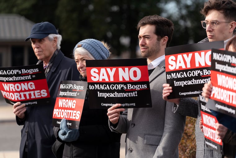 People hold up their signs as Rep. Jamie Raskin, D-Md., ranking member of the House Oversight and Accountability Committee, speaks during a news conference on Republican's impeachment inquiry into President Joe Biden at the U.S. Capitol on Dec. 13.