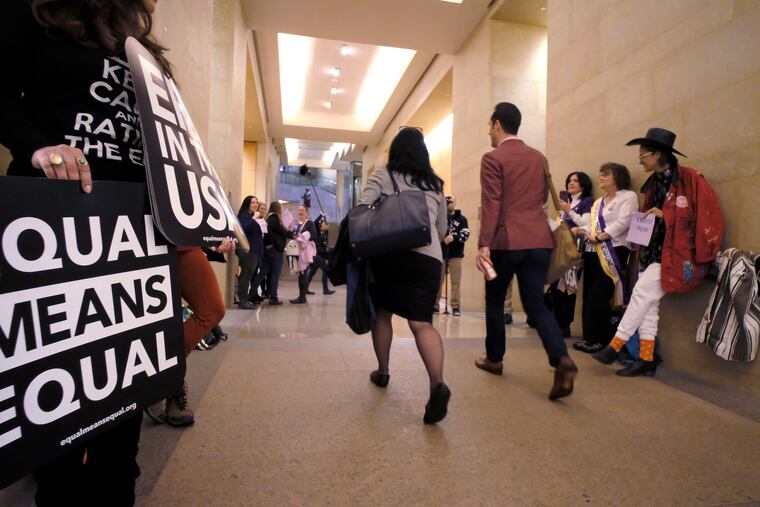 Equal Rights Amendment supporters yell encouragement to two legislators as they walk down a hallway inside the state Capitol in Richmond, Va. A new poll from The Associated Press-NORC Center for Public Affairs Research shows that roughly three in four Americans support the gender equality amendment.