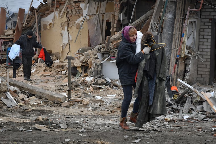 Local residents carry what is left of their belongings as they leave their destroyed home in Zaporizhzhya, Ukraine, on Sunday.