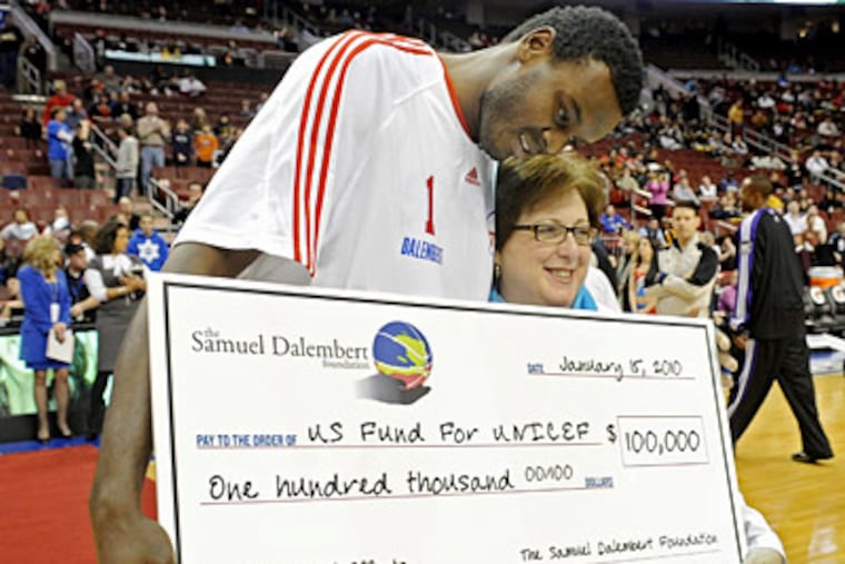 Samuel Dalembert hugs UNICEF's Caryl Stern as he presents her with a check for $100,000 to aid relief efforts in Haiti. (Clem Murray / Staff Photographer)