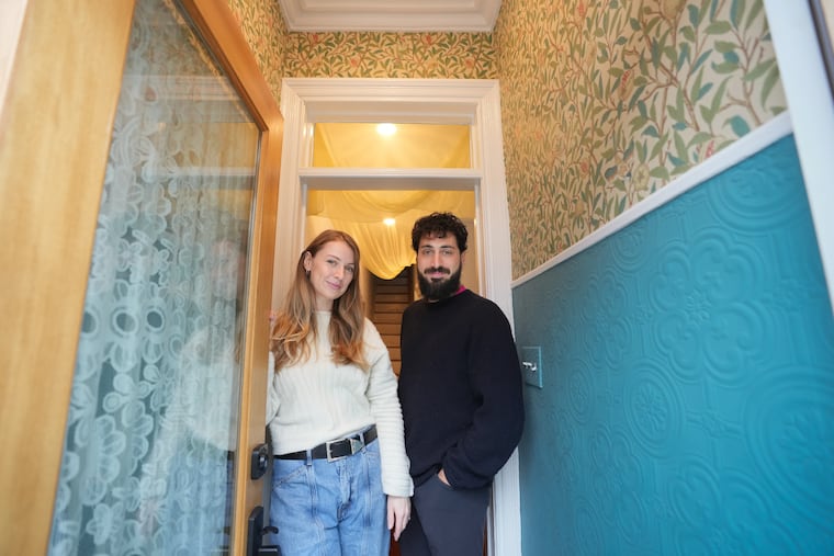 Sarah Schrading and Eli Steiker-Ginzberg in the vestibule of their home, where they chose a classic William Morris wallpaper called Bird and Pomegranate above the chair rail and a textured Anaglypta paper painted in Benjamin Moore Baltic Sea below.
