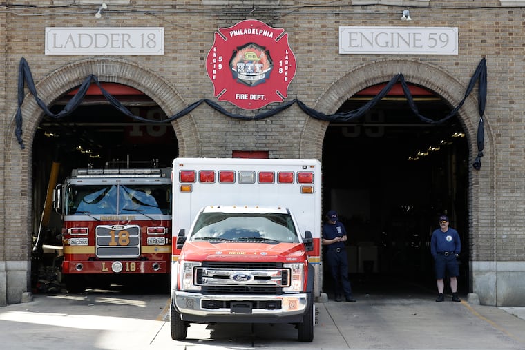 Philadelphia firefighters stand outside of station Ladder 18 Engine 59 with black bunting hung in honor of fallen firefighter Lt. Sean Williamson on Saturday.