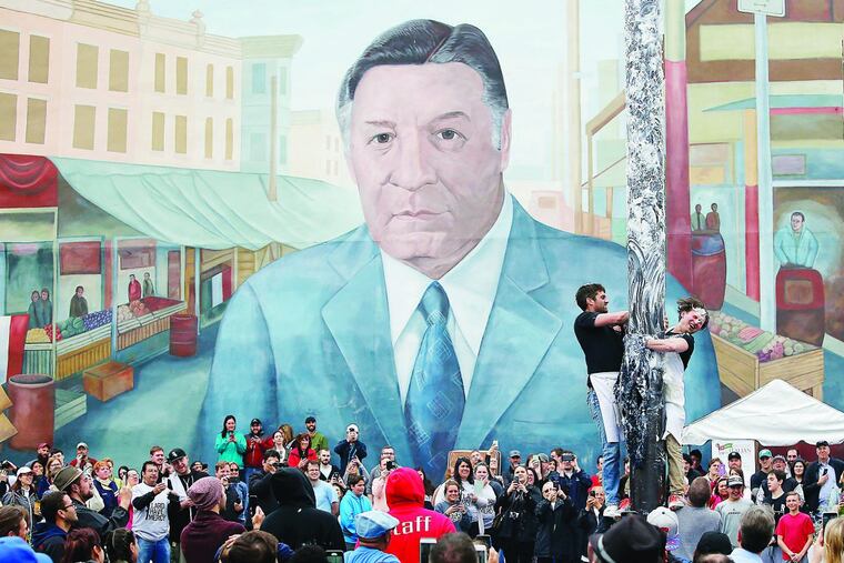Participants try to climb the greased pole with the mural of former Philadelphia Mayor Frank Rizzo looking on at the South 9th Street Italian Market Festival on Saturday, May 21, 2016.