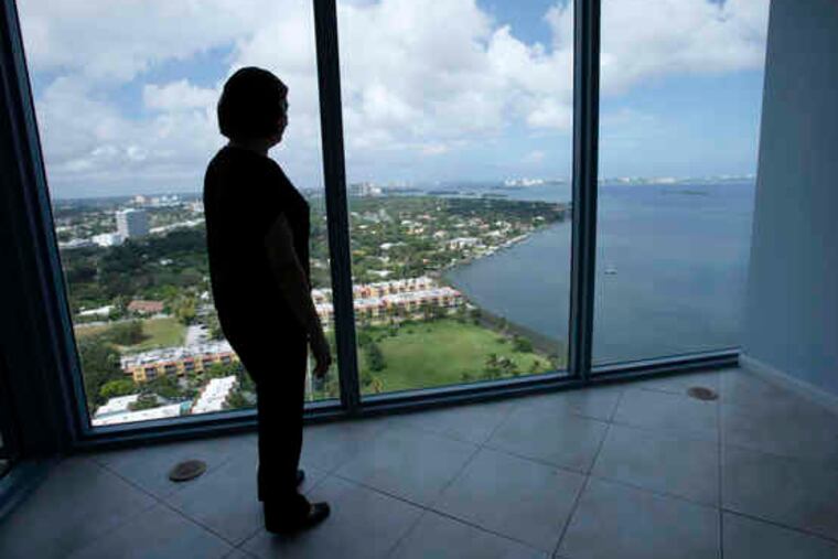 Above, prospective buyer Elsa de Blaschke , of Colombia, gazes out from a unit in The Blue condominium complex in Miami. At top, a "sale pending" sign on a home in Palo Alto, Calif., could be an encouraging indication.