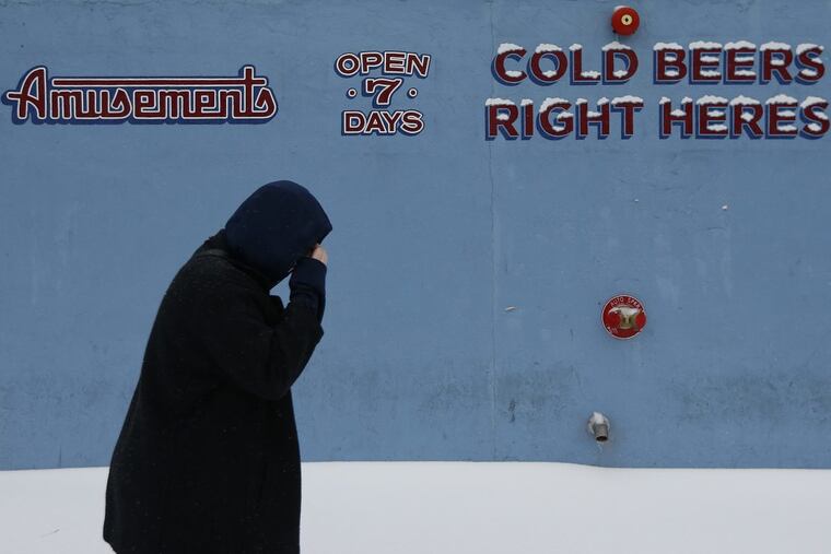 Maxine Van Osten, 16, of Fishtown, walks by the sign in from of the bar, Garage on Girard Avenue and Frankford Avenue during the winter storm last March. While there’s no storm on its way, the Philly region could get its first taste of snow by the end of this week.
