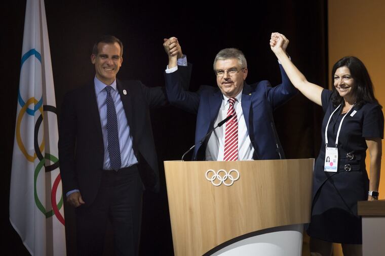 International Olympic Committee, IOC, president Thomas Bach (center) raises arms of mayor of Los Angeles Eric Garcetti and Anne Hidalgo, the mayor of Paris after announcing the two cities will host either the 2024 or 2028 Summer Games.