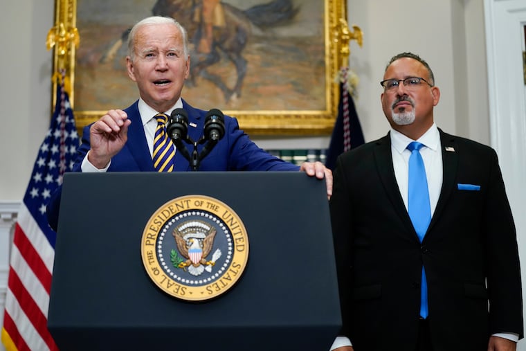 FILE - President Joe Biden speaks about student loan debt forgiveness in the Roosevelt Room of the White House, on Aug. 24, 2022, in Washington. Education Secretary Miguel Cardona listens at right. The White House is moving forward with a proposal that would lower student debt payments for millions of Americans now and in the future, offering a new route to repay federal loans under far more generous terms.