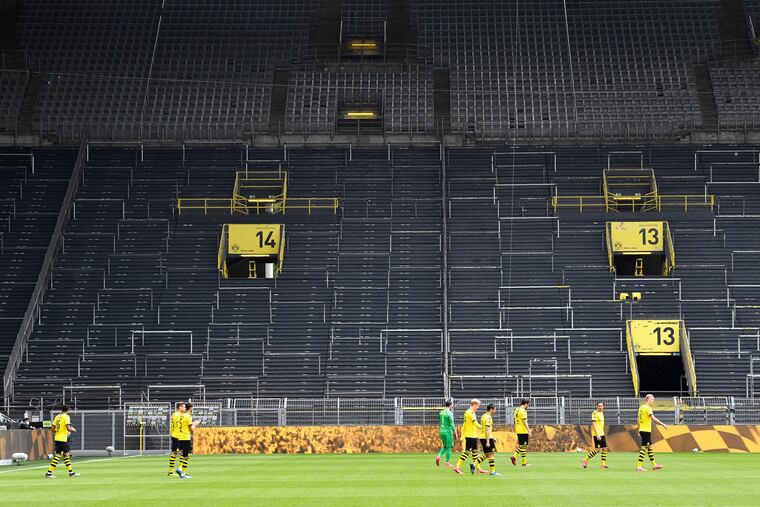 Borussia Dortmund players take the field in front of empty stands in the famous "Yellow Wall" end of their home stadium, Signal Iduna Park.