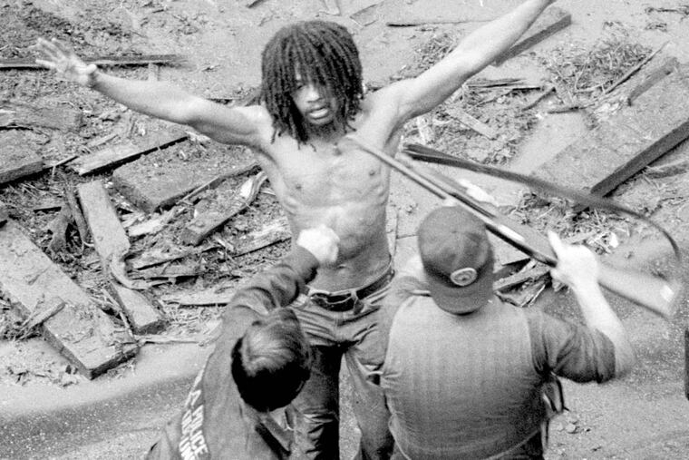 MOVE member Delbert Africa surrenders 8/8/1978 to police after a shoot out at MOVE headquarters in Philadelphia. James G. Domke / Inquirer Staff Photographer