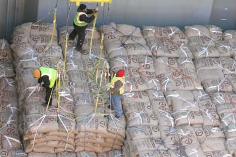Workers on board the Atlantic Tramp prepare to send over another load of about 150 bags of cocoa beans to trucks waiting alongside the vessel at a Camden port. They unload about 5,000 bags of beans in an hour of work. (Charles Fox / Staff Photographer)