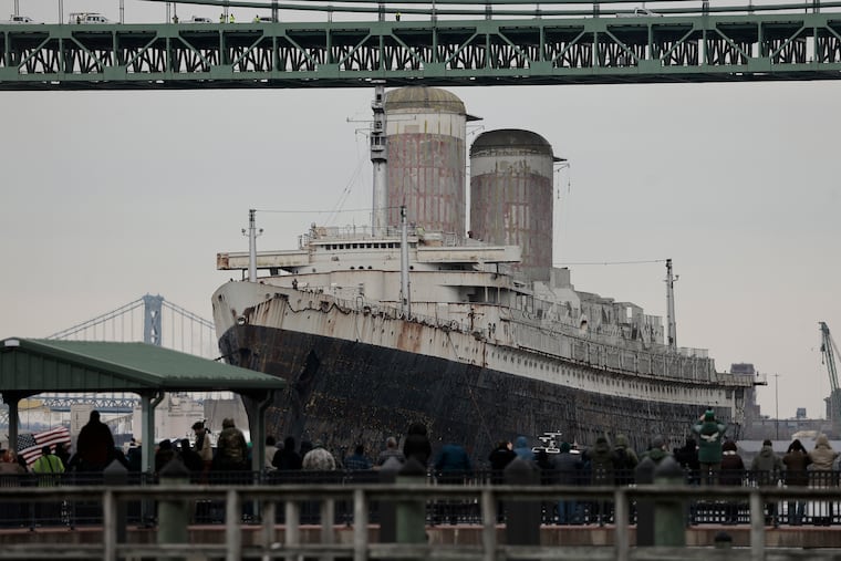 People watch from the Gloucester City Marina as the SS United States passes under the Walt Whitman Bridge while being towed down the Delaware River in Philadelphia on Feb. 19.