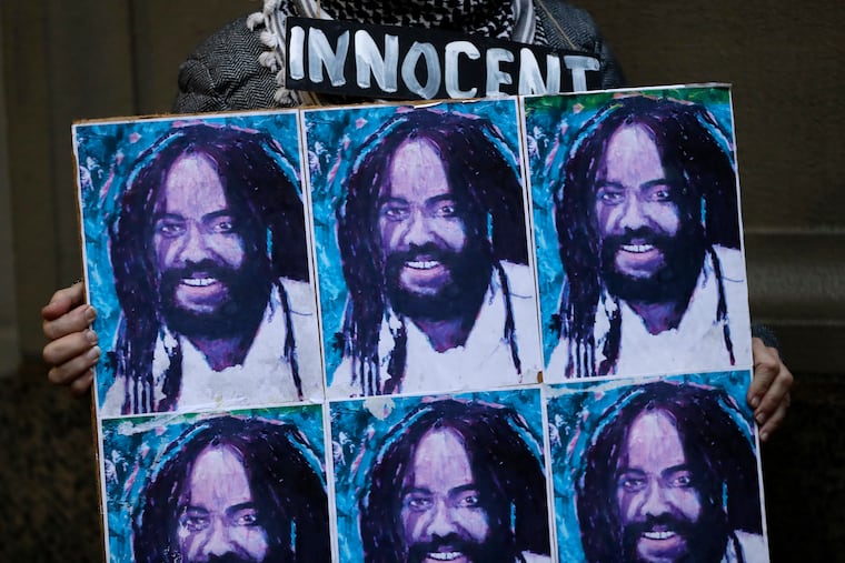 A protester holds up a poster depicting Mumia Abu-Jamal in Philadelphia in 2018, during a demonstration outside the offices of District Attorney Larry Krasner.