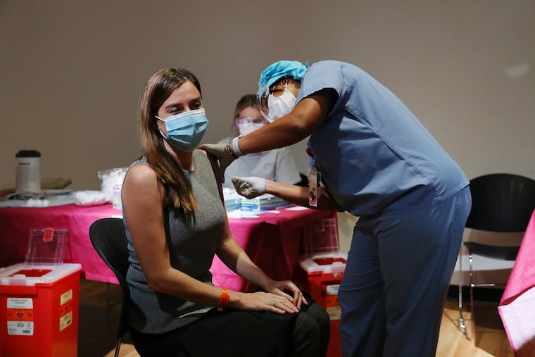 Chief Clinical Officer Dr. Claire Raab (left) receives her first dose of the Pfizer-BioNTech COVID-19 vaccine from nurse Shakay McClean at Temple University Hospital in North Philadelphia last week.