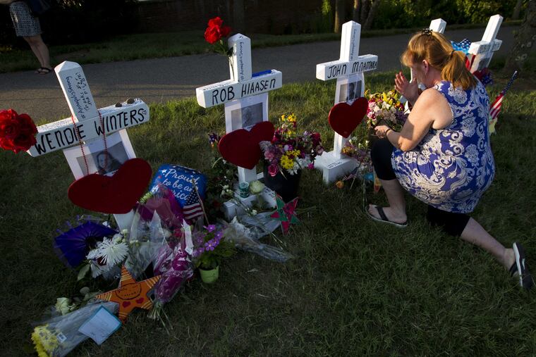 Colleen Joseph prays over the crosses at a makeshift memorial at the scene outside the office building housing The Capital Gazette newspaper in Annapolis, Md., on Sunday, July 1. ,