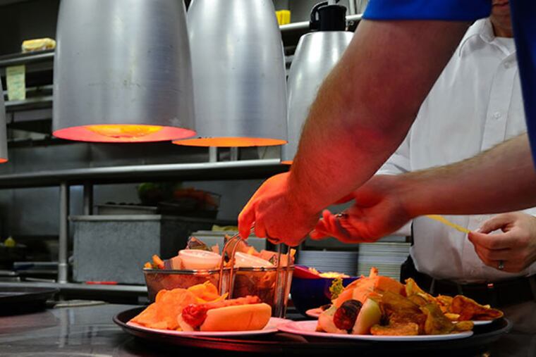 Kitchen staff at Harry the K's makes the final preparations on an order before it's taken out on Tuesday, June 10, 2014. (C.F. Sanchez / Staff Photographer)