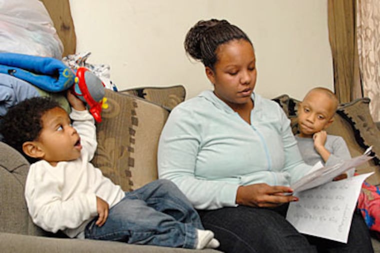Michelle Morgan reviews homework with her 7-year-old son, Evan Drake. Her younger son, Robert Franklin, 2, looks on. ( Jonathan Wilson / Staff Photographer )