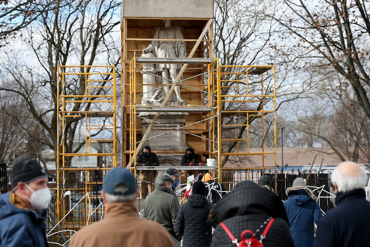 A team from Angelo's Marble & Granite Inc. inspect the condition of the Christopher Columbus statue in Marconi Plaza in Philadelphia on Jan. 27, 2021, when the box covering the statue was temporarily removed for the inspection.
