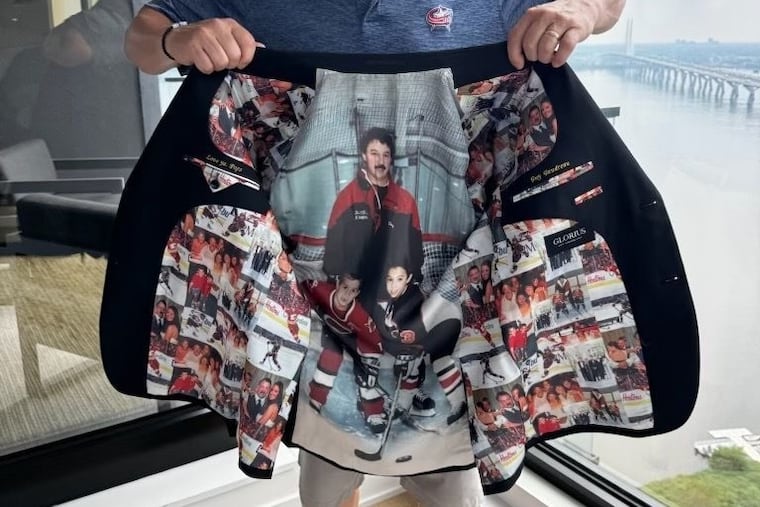 Guy Gaudreau holds up the custom suit that his daughter, Katie, surprised him with for her wedding. Montreal designer J.F. Bedard designed the suit to honor his two sons, Matthew and Johnny, who died after being struck by a alleged drunk driver in August 2024 after Katie's rehearsal dinner.