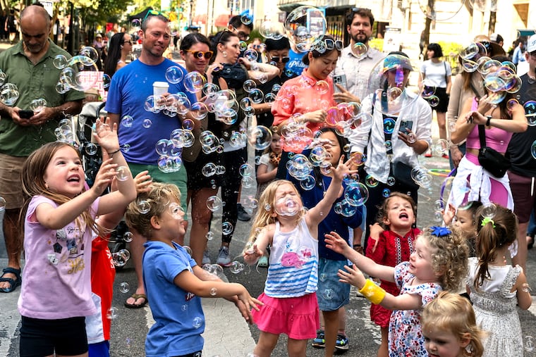 Children enjoy soap bubbles at the intersection of 18th & Walnut Streets. The streets around Rittenhouse Square closed to vehicular traffic for the city's Open Streets program. Philadelphia should expand the concept, writes Yadan Luo.