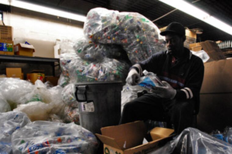 At TerraCycle, Kenneth Martin cuts labels from recycled bottles. The company uses recycled plastic milk jugs and soda bottles collected by schoolchildren to package its products.