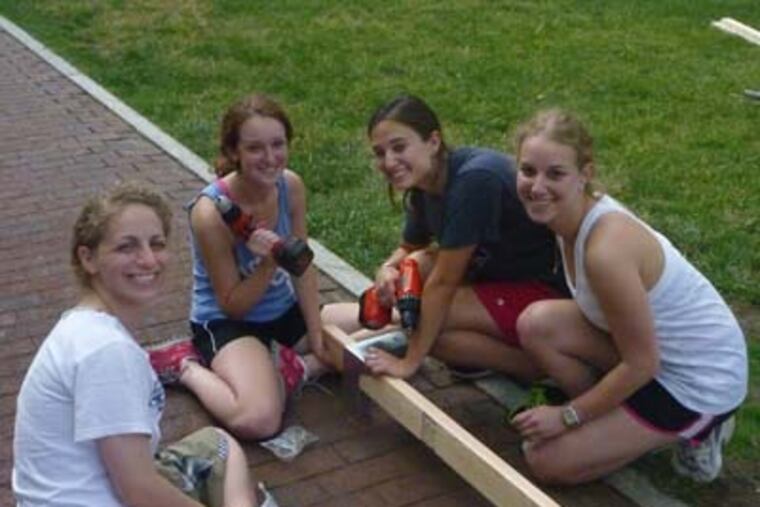 At the University of Pennsylvania campus, sukkathon project coordinator Naomi Hachen, far left, works at building a sukka with team Wear-Care. Second from left is Jessica Marder; third from left is Melissa Goldstein, name of fourth girl is Aliza Keller. Photo by Joe Trinacria