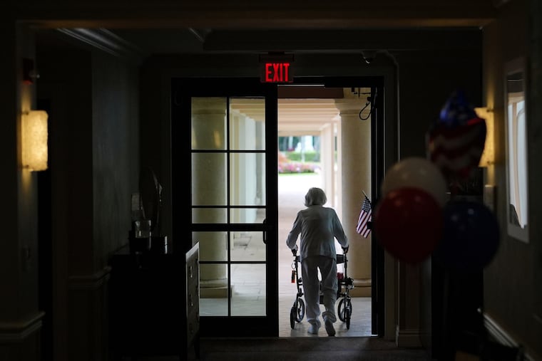 FILE - A woman uses a walker as she exits an assisted living building, July 4, 2025, in Boca Raton, Fla.