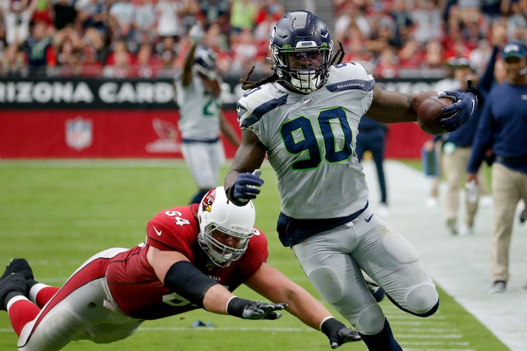 Jadeveon Clowney (90) runs back an interception for a touchdown as Arizona Cardinals offensive guard J.R. Sweezy (64) defends in September.