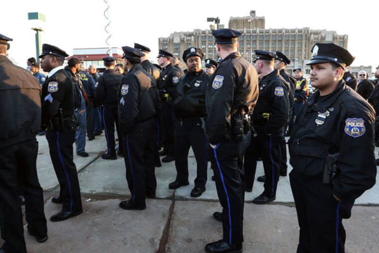 Police officers listen to speakers at a prayer vigil held Monday outside the North Philadelphia GameStop where Officer Robert Wilson was fatally shot during an attempted robbery Thursday. STEVEN M. FALK / STAFF PHOTOGRAPHER