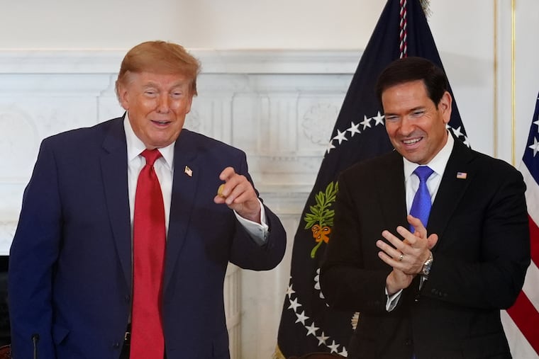 President Donald Trump holds a gold nugget he was presented as Secretary of State Marco Rubio watches during a roundtable on the American mining industry Friday at the State Department in Washington.