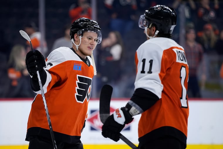 The Flyers' Matvei Michkov (left) recorded his first NHL point in Saturday's game against the Flames, setting up Travis Konecny for a goal.