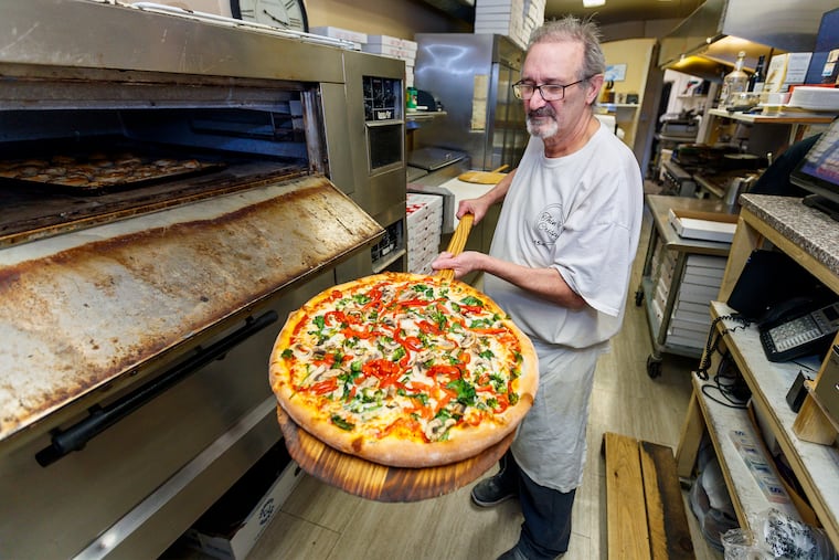 Franco Buscemi, owner of Thin & Crispy Pizza, pulls a Vegetarian Delight large pizza out of the oven at his pizzeria on Trenton Avenue.