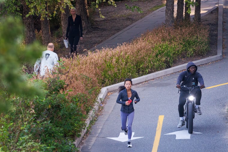 Runner at left being passed on the Schuylkill River Trail by an e-bike.