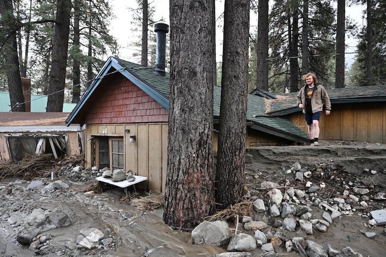 Davey Schneider walks on the roof of his storm-damaged home on Thursday in Wrightwood, Calif.