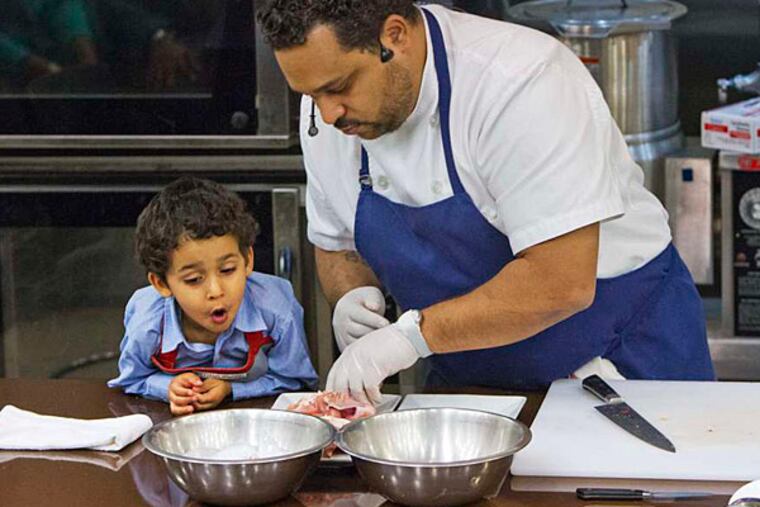 Chef Kevin Sbraga and his son Angelo cook for an audience gathered at the college's culinary center. (David M Warren/Staff)