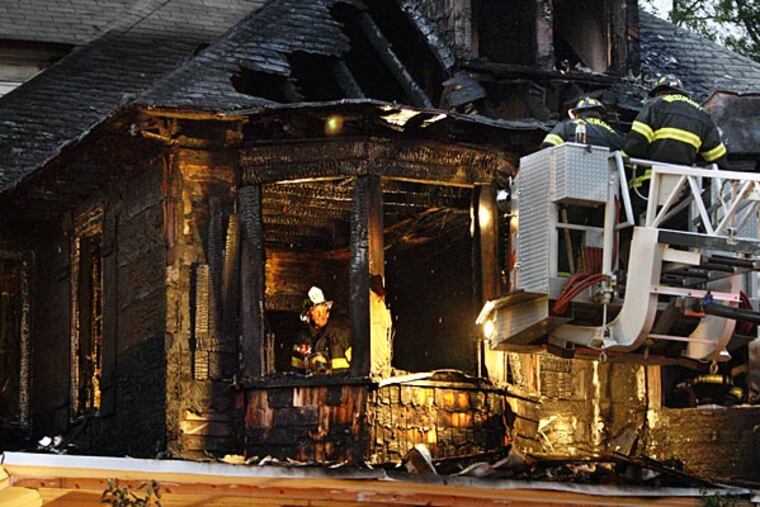 Firefighters work to extinguish hot spots and get more light on the second floor as they search for the cause of a two-alarm fire that nearly destroyed 205 Emerald Ave. in Haddon Township and damaged the neighboring twin home at 207 Emerald Ave.