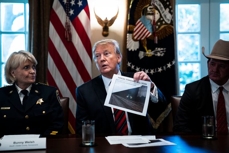 President Donald Trump holds up a photo of a "typical standard wall design" as he speaks during a roundtable discussion on border security with administration officials at the White House on Jan. 11, 2019.