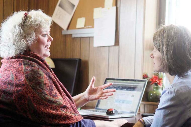 Holly Phares (left) explains to Laura Line how she got into the federal health care website at the Resources for Human Development office in Roxborough. In Pa., a state plan for low-income people who otherwise don't have or can't afford health care is in jeopardy with Gov.-elect Tom Wolf.