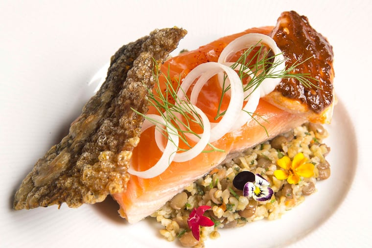 Crispy salmon skin, leek rings, fennel fronds, and a cube of salmon with harissa.